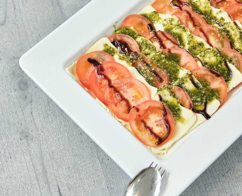 Vorspeisenplatte Caprese mit grüner Pesto garniert