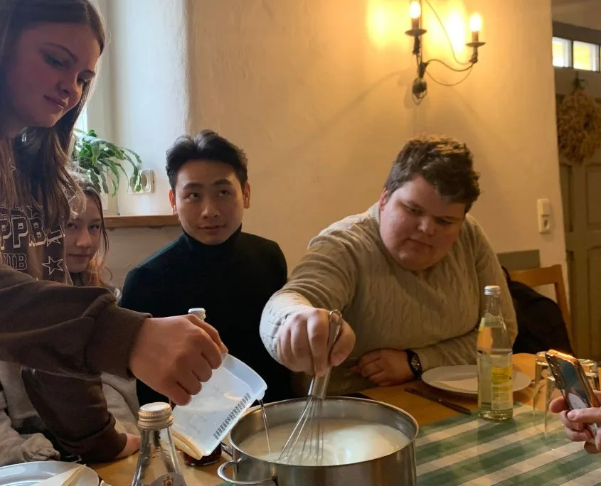 Auszubildende beim Käseseminar rühren Milch im Topf Auszubildende beim Käseseminar
