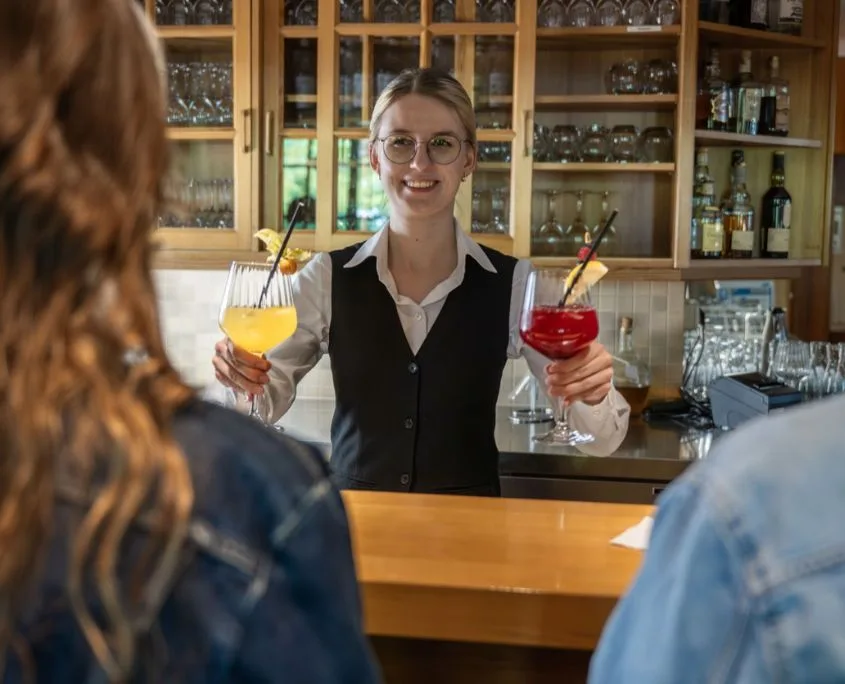 Servicemitarbeiterin serviert roten und gelben Cocktail an der Theke Service im Seehof Restaurant