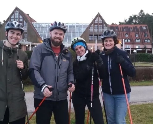Familie mit Walkingstöcken und einem Helm auf dem Kopf, stehen vor dem Strandhotel Seehof